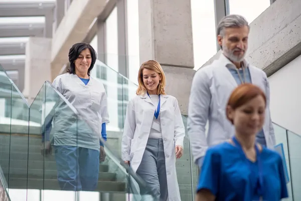 Médicos en Alemania bajando unas escaleras, tres de ellos utilizan batas blancas