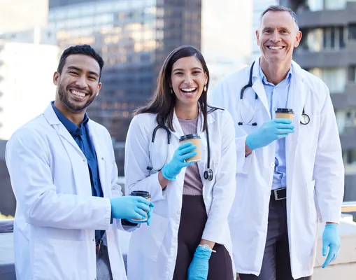 Tres médicos en Alemania tomando café, sonriendo y posando para la cámara