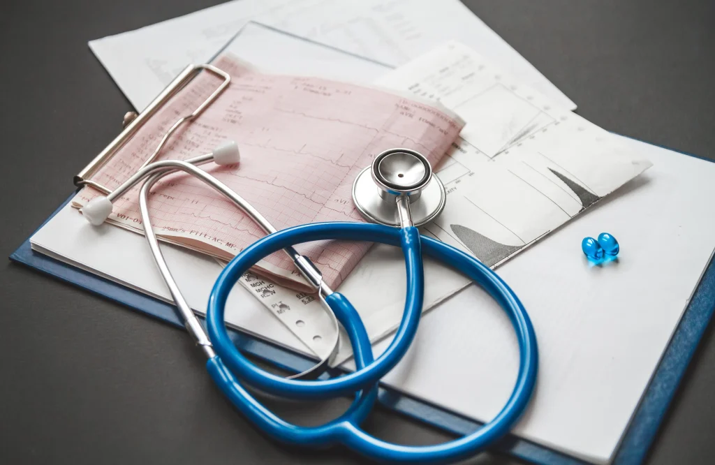 Estetoscopio azul y documentos que ayudan a ilustrar ¿Cómo conseguir tu primer empleo como médico en Alemania?