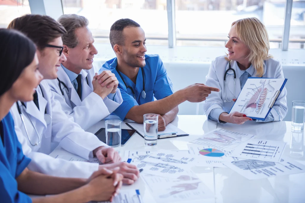 Médicos revisando documentos sentados en una mesa, ejemplificando ¿Cómo conseguir tu primer empleo como médico en Alemania?