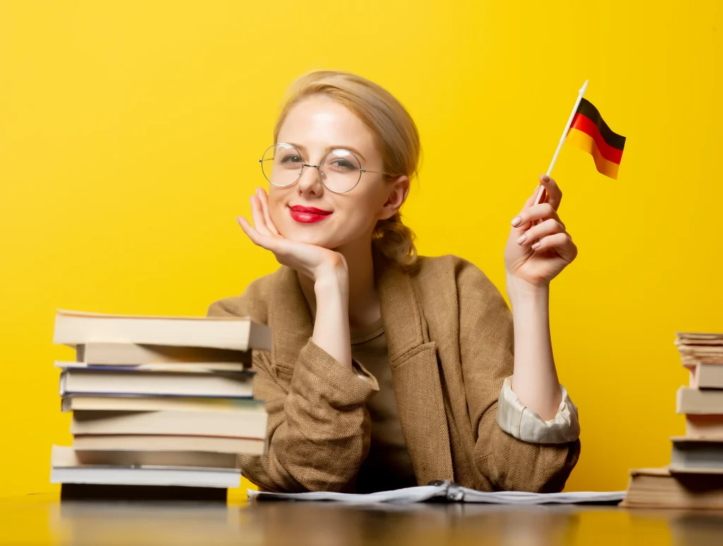 Mujer con bandera de Alemania y libros, simboliza ¿Qué nivel de alemán necesitas para trabajar como médico en Alemania?